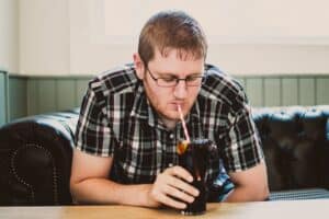 man sipping drink from clear glass