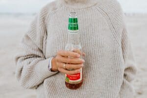 woman in sweater holding a beer bottle